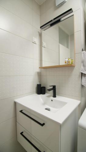 La salle de bains blanche est pourvue d'un lavabo et d'un miroir. dans l'établissement LocOs Sjenjak, à Osijek
