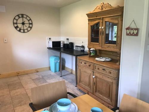 eine Küche mit einem Holzschrank und einem Tisch in der Unterkunft Rosie's Pad in Mayo