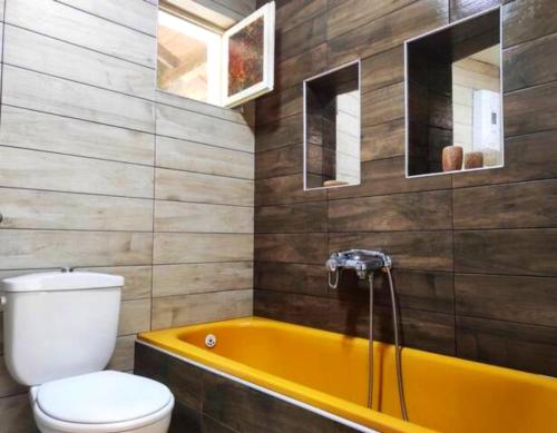 a bathroom with a yellow tub and a toilet at Villa Forest Paradise in Ohrid