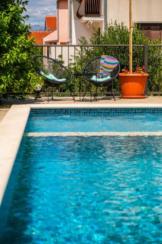 a swimming pool with two chairs and a swimming pool at Villa Josipa with Private Heated Pool & Close to Beach in Supetar