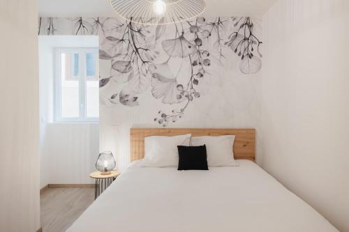 a bedroom with a white bed and a chandelier at Charmant T3 en Centre Ville #1 in Embrun