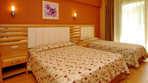 a bedroom with two beds and a dresser at Grand Pasa Hotel in Marmaris