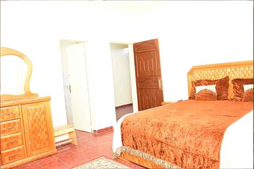 a bedroom with a bed and a dresser and a mirror at Jolie Maison in Nouakchott