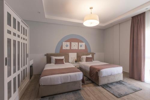 a bedroom with two beds and a large window at Gewan Resort New Alamein in El Alamein