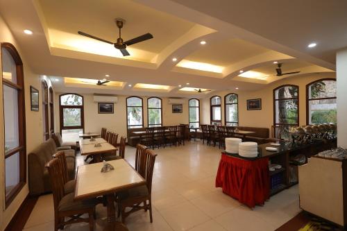 a restaurant with wooden tables and chairs and windows at Riverside Resorts in Devaprayāg