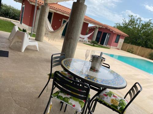 a glass table and chairs next to a pool at Verde Oliva Residence in Ispica