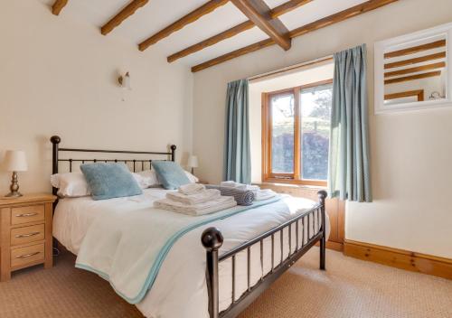 a bedroom with a bed with blue pillows and a window at Oak Lodge Cottage in Grasmere