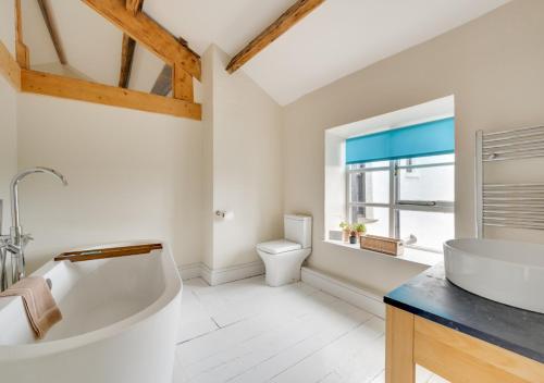 a white bathroom with a tub and a toilet at Fell View in Silecroft