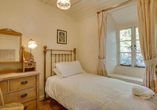 a bedroom with a bed and a dresser and a window at Slaters Cottage in Little Langdale