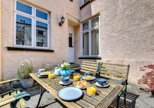 a wooden table with plates of food on a patio at Elterwater Apartment in Bowness-on-Windermere
