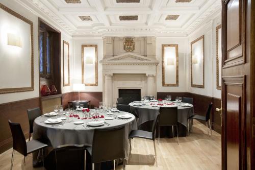 a dining room with tables and chairs and a fireplace at Boutique Hotel H10 Villa de la Reina in Madrid