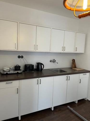 a kitchen with white cabinets and a sink at Penzion U Radnice in Doksy