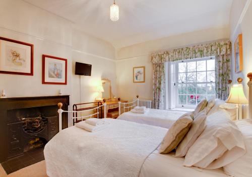 a bedroom with two beds and a fireplace at Crag Head Cottage in Ambleside