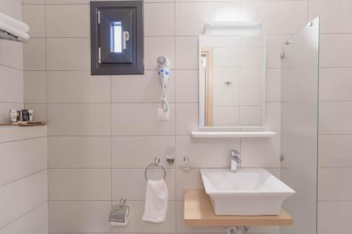 a white bathroom with a sink and a mirror at 1951 Suites in Kalabaka