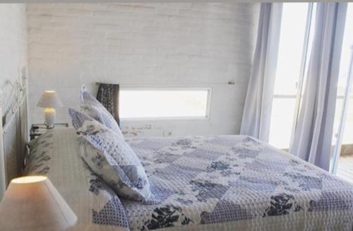 a bedroom with a bed with a blue and white quilt at Miralejos in Punta Del Diablo