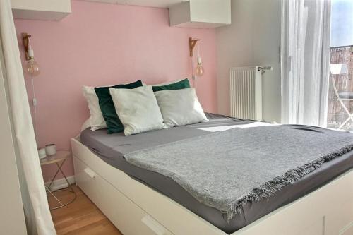 a bedroom with a large bed with pink walls at Le Toît du Montvalerien Suresnes in Suresnes