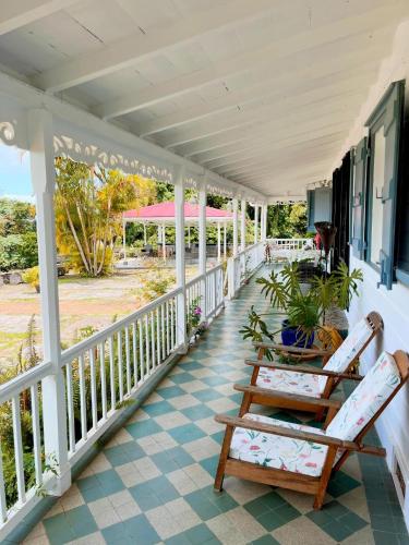 a porch with two chairs and a table at Habitation La Reine du Camp Chambres d'Hôtes in Saint-Claude