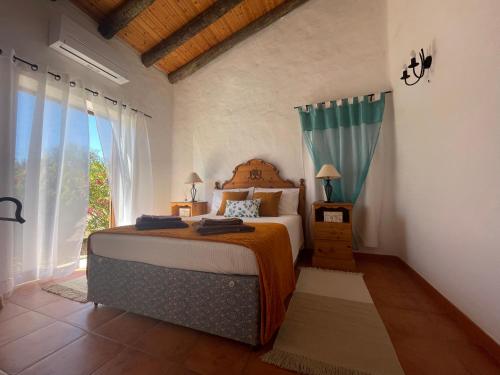 a bedroom with a bed and a large window at Monte da Azinheira in Ourique