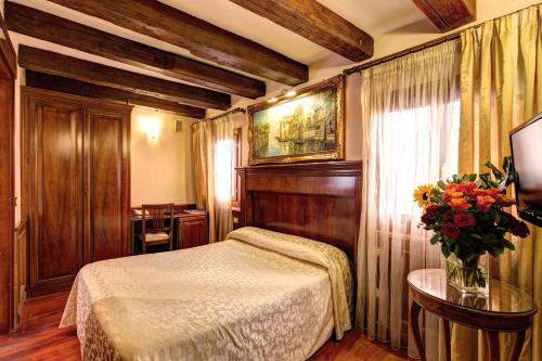 sypialnia z łóżkiem i wazonem kwiatów w obiekcie Palazzo La Scala w Wenecji
