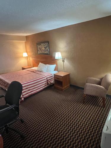 a hotel room with a bed and a desk and chairs at The Lodge Hotel and Banquets in Bridgeton
