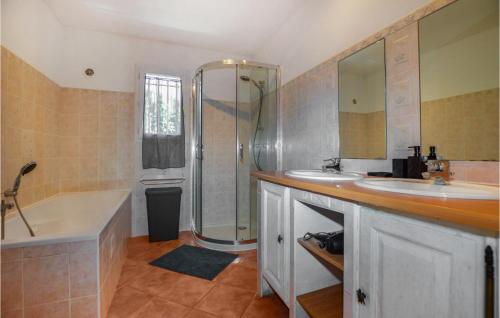 La salle de bains est pourvue d'une baignoire, de 2 lavabos et d'une douche. dans l'établissement 3 Bedroom Nice Apartment In Bastelicaccia, à Bastelicaccia