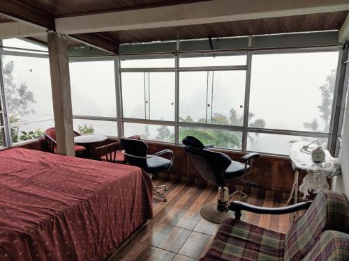 een kamer met een bed, stoelen en ramen bij Rohana Estate Lodging & Camping in Kandy