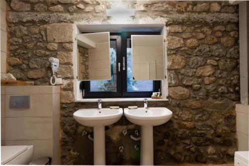 a bathroom with two sinks and a stone wall at 1951 Suites in Kalabaka