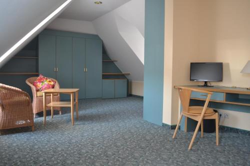 a room with a desk with a tv and chairs at Hotel Wehlener Hof in Stadt Wehlen