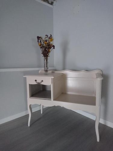 une console blanche avec un vase de fleurs sur elle dans l'établissement La Croisée Des Chemins, à Maisonnais-sur-Tardoire