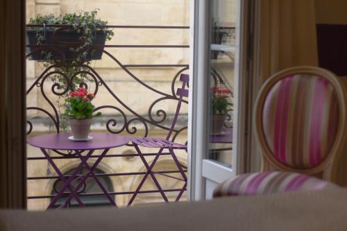 a table with chairs and a vase of flowers at Au Coeur de Bordeaux - B&B et Cave à vin in Bordeaux