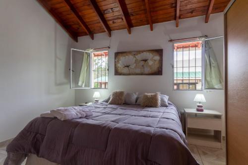 a bedroom with a large bed and two windows at Cabañas Noscohue in Villa General Belgrano