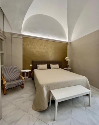 a bedroom with a large bed and a chair at Palác Daun - Studio Apartments in Znojmo