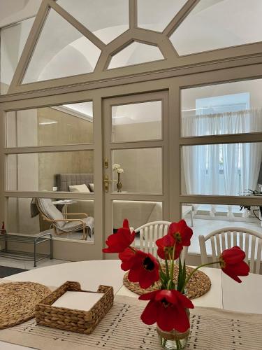 a dining room with a table with red flowers on it at Palác Daun - Studio Apartments in Znojmo