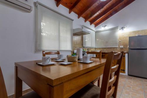 a kitchen with a wooden table with chairs and a refrigerator at Cabañas Noscohue in Villa General Belgrano