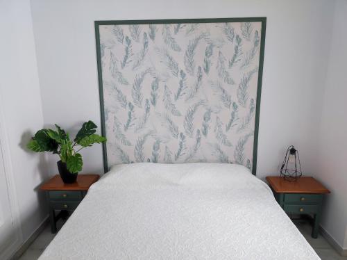 a bedroom with a white bed with two tables and a plant at Florencio Quintero Home in Seville