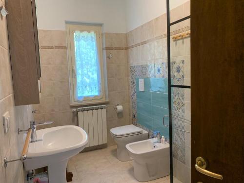 ein Bad mit einem Waschbecken, einem WC und einem Fenster in der Unterkunft Butterflies Rest in Gubbio