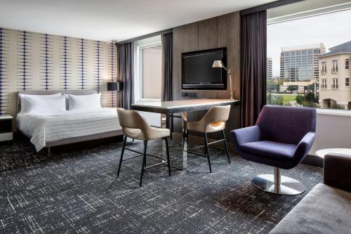a hotel room with a bed and a desk and chairs at Le Meridien Dallas by the Galleria in Dallas