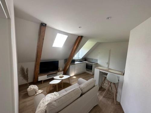 a living room with a white couch and a kitchen at Bel appartement cosy proche de la frontière Suisse in Villers-le-Lac