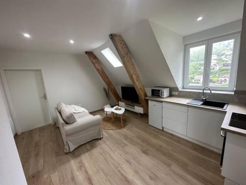 a living room with a chair and a kitchen at Bel appartement cosy proche de la frontière Suisse in Villers-le-Lac