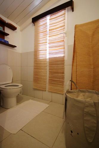 a bathroom with a toilet and a window at MADIROKELY HOUSE Nosy Be in Ambatoloaka