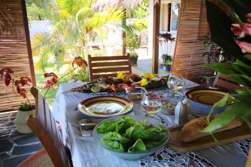 a table with plates of food and salad on it at MADIROKELY HOUSE Nosy Be in Ambatoloaka