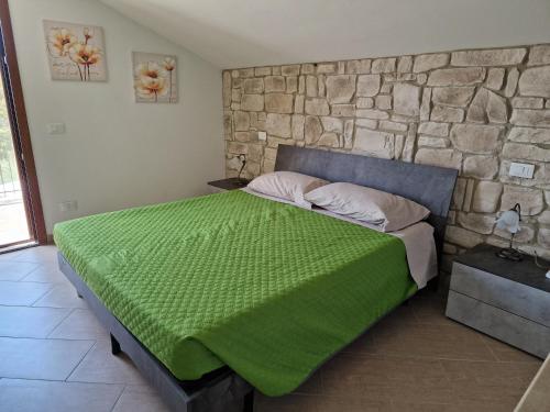 a bedroom with a bed with a green blanket on it at Il Panorama in Montescudaio