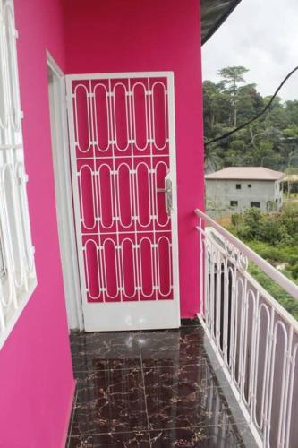 a pink house with a pink door on a balcony at Appartement Neuf à Odza in Yaoundé