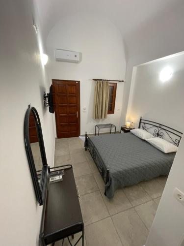 1 dormitorio con cama y espejo en Tarelis Apartments & Studios, en Kamari