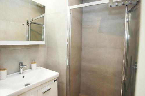 La salle de bains est pourvue d'une douche et d'un lavabo blanc. dans l'établissement InTown Suite, à Leucade