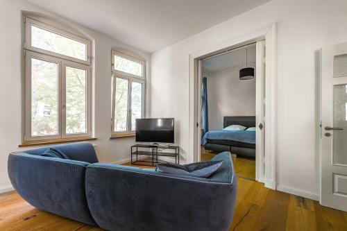 a living room with a blue couch and a bed at Modernes City-Apartment mit Blick in den Park und 2 Bäder H9 in Oldenburg