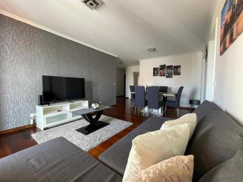 a living room with a couch and a flat screen tv at Por do Sol in Caniço