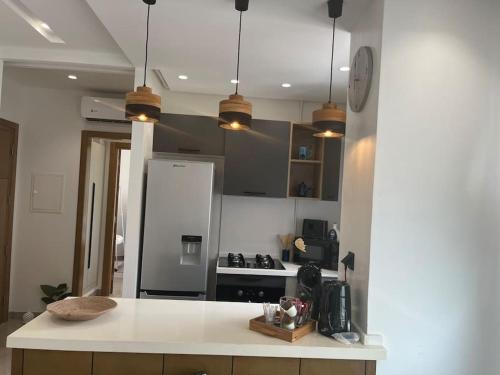 a kitchen with a white counter top and a refrigerator at Appartement avec piscine et 10 min plage in Hammamet Nord