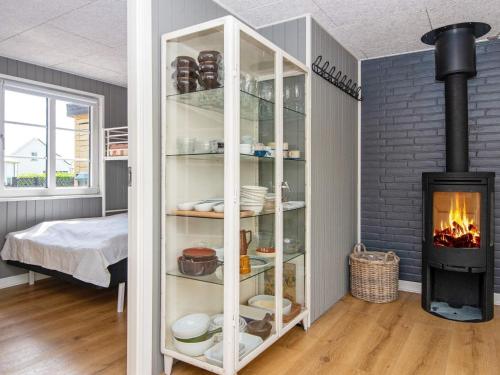 um quarto com lareira e uma estante de livros com pratos em Holiday home Hejls LIII em Hejls