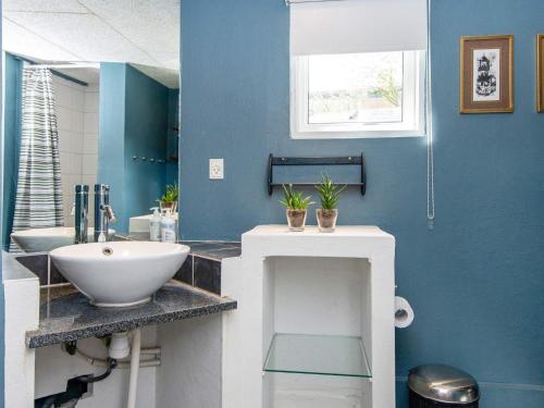 uma casa de banho com um lavatório branco e uma parede azul em Holiday home Hejls LIII em Hejls